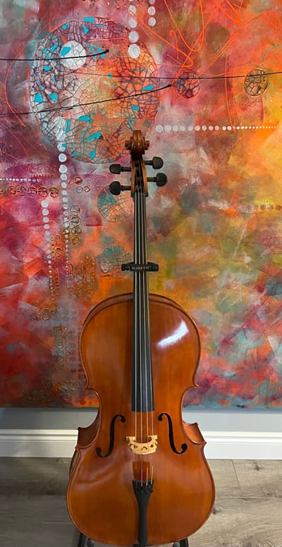 Cello displayed in front of a Peg Kivi painting